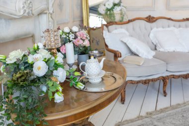 İçi bej renkli, zengin oturma odası. Barok tarzı antika pahalı mobilyalar. Duvarlar sıva ve fresklerle süslenmiş.