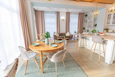 Modern, pahalı, lüks, açık planlı bir daire. Tavanda pastel renkli ahşap kirişler olan zengin İskandinav tarzı iç mekan.