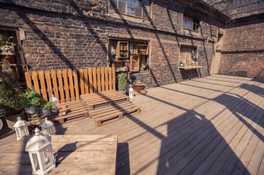 Verandanın çatı katı tasarımı. Ahşap süslemeler. yeşil bitkiler