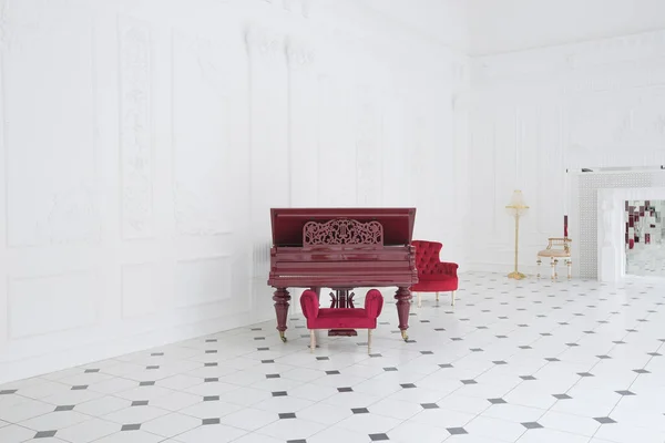 stock image Huge luxury white hall with unique interior. Black and white tiles on the floor, white and black stucco on the walls, high fireplace with mirror mosaic, three-meter crystal chandelier and grand piano