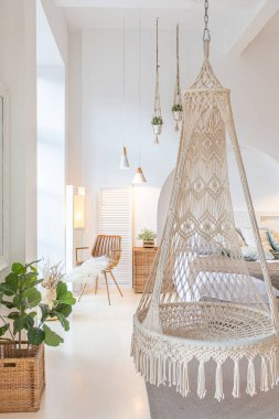 Tavan arasında ahşap sütunlar olan, tuğla, mermer, ahşap, şık mobilyalar ve beyaz duvarlarla süslenmiş, aydınlık bir stüdyo dairesinin modern iç mimarisi.