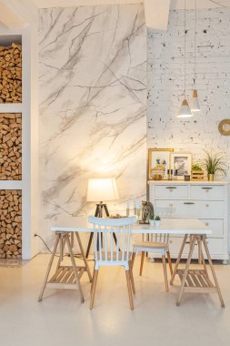 Tavan arasında ahşap sütunlar olan, tuğla, mermer, ahşap, şık mobilyalar ve beyaz duvarlarla süslenmiş, aydınlık bir stüdyo dairesinin modern iç mimarisi.