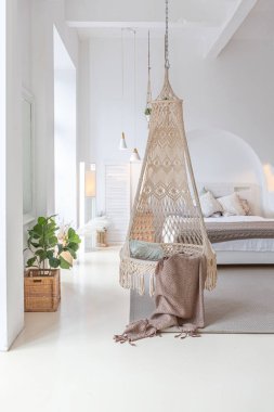 Tavan arasında ahşap sütunlar olan, tuğla, mermer, ahşap, şık mobilyalar ve beyaz duvarlarla süslenmiş, aydınlık bir stüdyo dairesinin modern iç mimarisi.