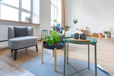 Şık bir çatı katının içinde. Geniş pencereli, yerde parke ve aydınlık duvarlı geniş bir daire. Dekorasyon için farklı küçük şeylerle rafların yakın görüntüsü