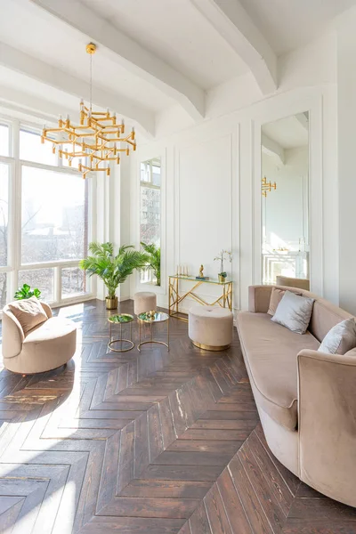 富丽堂皇的舒适客厅里明亮明亮的内部 有别致柔软的米黄色家具 带有金金属元素 有巨大的地板窗户和木制花篮 — 图库照片