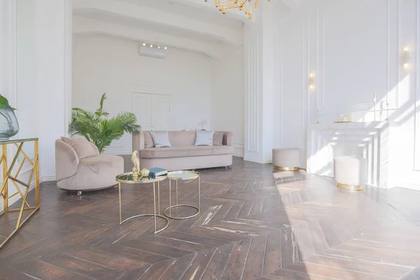 富丽堂皇的舒适客厅里明亮明亮的内部 有别致柔软的米黄色家具 带有金金属元素 有巨大的地板窗户和木制花篮 — 图库照片