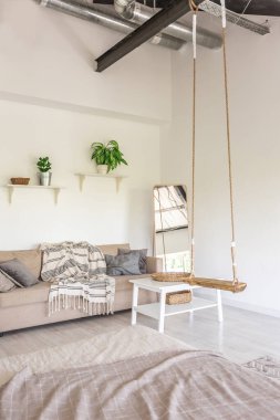 Minimalist tarzda bir kır evinde lüks yatak odası tasarımı. Beyaz duvarlar, panoramik pencereler, tavanda ahşap süslemeler, geniş bir odanın ortasında sallanan ip..