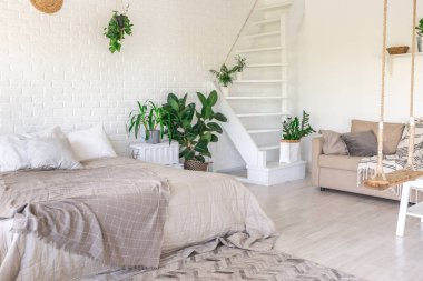 Minimalist tarzda bir kır evinde lüks yatak odası tasarımı. Beyaz duvarlar, panoramik pencereler, tavanda ahşap süslemeler, geniş bir odanın ortasında sallanan ip..