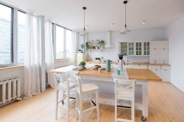 Geniş pencereli, modern, dubleks bir dairede açık renkli şık bir mutfak..