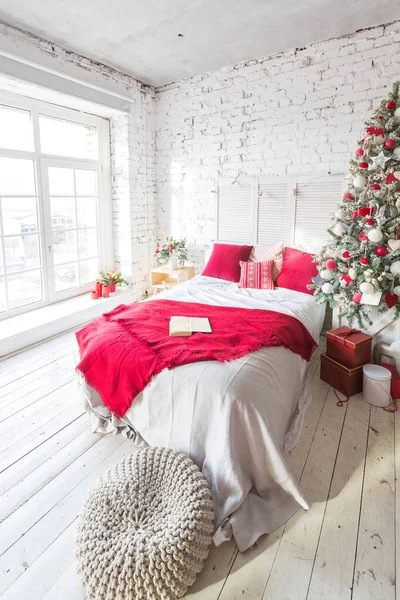 stock image A spacious white light bedroom in a loft style with a decorated Christmas tree and a garland.