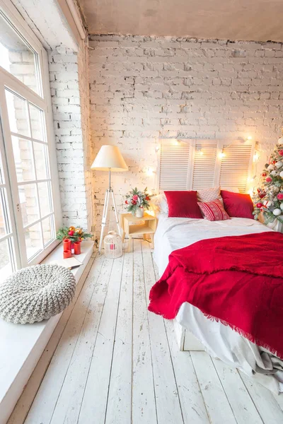 stock image A spacious white light bedroom in a loft style with a decorated Christmas tree and a garland.