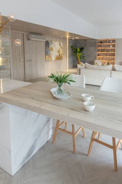 Beyaz ve bej renkli geniş tabandan tavana kadar pencereleri olan büyük bir stüdyonun modern iç tasarımı. Adayı ve dinlenme alanı olan beyaz mutfak.