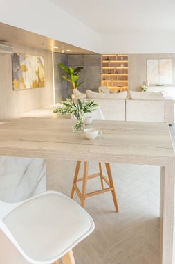 Beyaz ve bej renkli geniş tabandan tavana kadar pencereleri olan büyük bir stüdyonun modern iç tasarımı. Adayı ve dinlenme alanı olan beyaz mutfak.