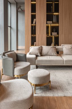 Oturma odası, mermer şömine ve lüks kır evinin şık iç mekanında şık bir kitaplık. Ahşap ve kurşun ışıklı modern bir tasarım, altın elementli gri mobilyalar.