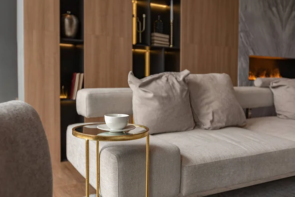 リビングルーム 大理石の壁の暖炉と金の要素を持つ光 灰色の家具を主導したモダンなデザインの高級カントリーハウスのシックな高価なインテリアでスタイリッシュな本棚 — ストック写真