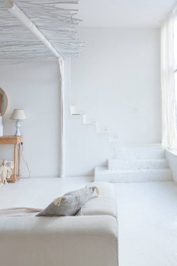 Beyaz duvarları, bambu koltuğu, büyük beyaz kanepesi ve süslemeleri olan Bali tarzı parlak bir dairenin içi.