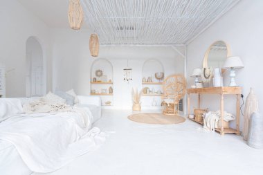 Beyaz duvarları, bambu koltuğu, büyük beyaz kanepesi ve süslemeleri olan Bali tarzı parlak bir dairenin içi.