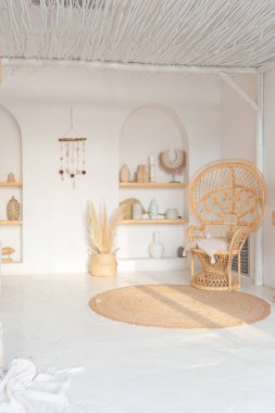 Beyaz duvarları, bambu koltuğu, büyük beyaz kanepesi ve süslemeleri olan Bali tarzı parlak bir dairenin içi.