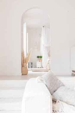 Beyaz duvarları, bambu koltuğu, büyük beyaz kanepesi ve süslemeleri olan Bali tarzı parlak bir dairenin içi.