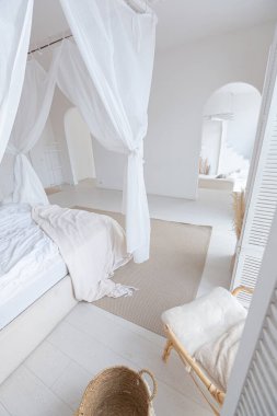 Beyaz duvarları, bambu mobilyaları olan, Bali tarzı parlak bir dairenin içi. Gece lambalı yatak odası, dengeli yatak ve geniş pencereli.