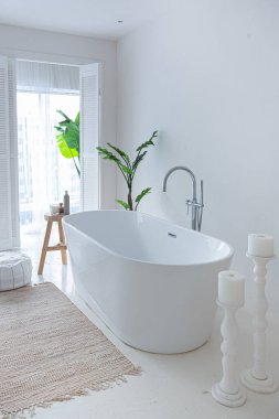 Extra white and very light minimalistic stylish elegant interior of bathroom with modern bath, green plants and wooden elements clipart