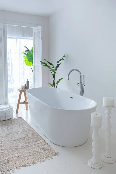 Stock image Extra white and very light minimalistic stylish elegant interior of bathroom with modern bath, green plants and wooden elements