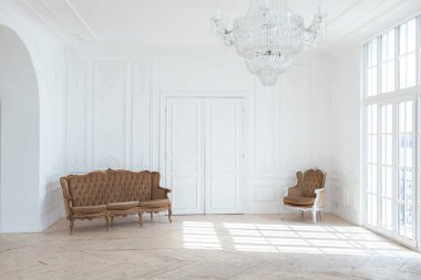 Pahalı antika mobilyaları olan büyük, şık bir salon. Barok iç tasarımı, duvarlarda süs ve yerde parke var..
