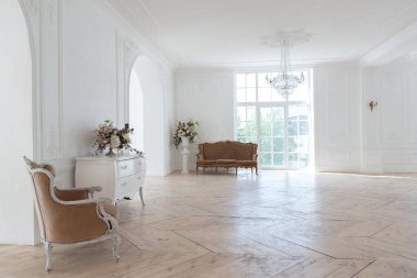 Pahalı antika mobilyaları olan büyük, şık bir salon. Barok iç tasarımı, duvarlarda süs ve yerde parke var..