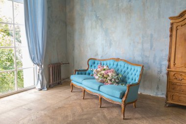 Güzel, antika barok mavi mobilyalar, ahşap parke ve lüks çiçeklerle dolu rahat bir oturma odası. Gündüz ılık yumuşak ışık.