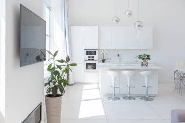 Minimalist tarzda pahalı mobilyaları olan ekstra beyaz renkli bir stüdyo dairenin lüks modern iç tasarımı. beyaz fayanslı zemin, mutfak, rahatlama alanı ve işyeri