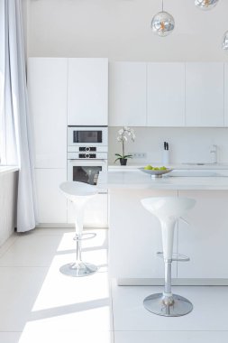 Minimalist tarzda pahalı mobilyaları olan ekstra beyaz renkli bir stüdyo dairenin lüks modern iç tasarımı. beyaz fayanslı zemin, mutfak, rahatlama alanı ve işyeri