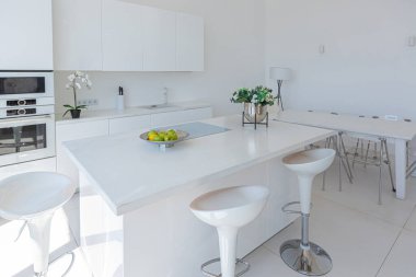 Minimalist tarzda pahalı mobilyaları olan ekstra beyaz renkli bir stüdyo dairenin lüks modern iç tasarımı. beyaz fayanslı zemin, mutfak, rahatlama alanı ve işyeri