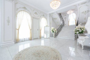 Barok tarzında lüks kraliyet iç mimarisi. Pahalı eski tarz mobilyaları olan aydınlık ve beyaz bir salon. İkinci kata çıkan şık geniş mermer merdiven.