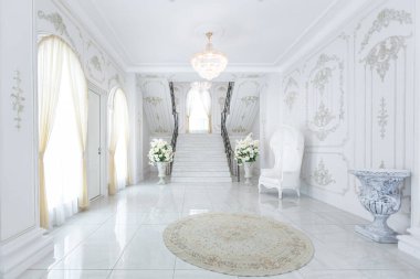 Barok tarzında lüks kraliyet iç mimarisi. Pahalı eski tarz mobilyaları olan aydınlık ve beyaz bir salon. İkinci kata çıkan şık geniş mermer merdiven.
