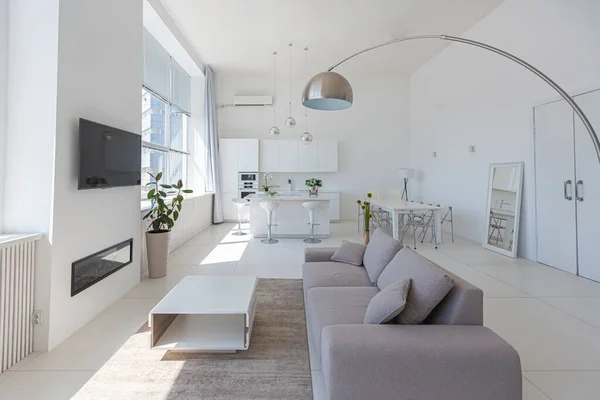 stock image Cozy luxury modern interior design of a studio apartment in extra white colors with fashionable expensive furniture in a minimalist style. white tiled floor, kitchen, relaxation area and workplace