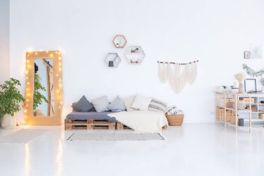 Geniş, ferah, şık, açık bir Bali tarzı dairesi asılı yatağı ve panoramik pencereleri var. Beyaz zemin ve duvarlar, basit ahşap mobilyalar..