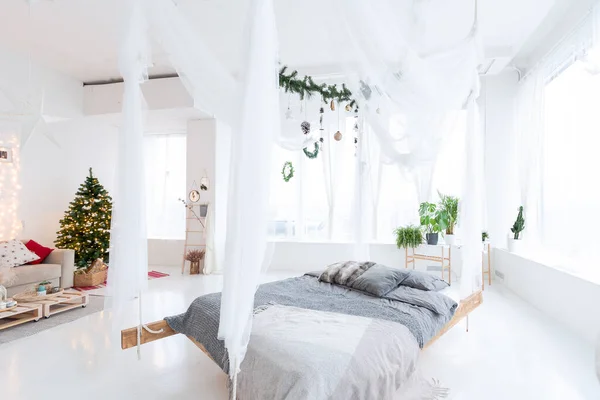 stock image large very bright spacious stylish open plan Bali style apartment with hanging bed and panoramic windows. white floor and walls, simple wooden furniture. decorated with a christmas tree