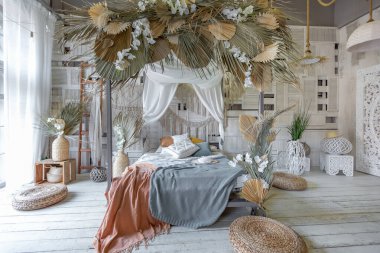Bali tarzı yatak odasının içi. Dekorasyon için bir sürü tekstil ve yumuşak pastel renklerde hasır eşyalar içeren tenteli yatak.