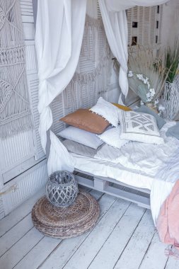 Bali tarzı yatak odasının içi. Dekorasyon için bir sürü tekstil ve yumuşak pastel renklerde hasır eşyalar içeren tenteli yatak.