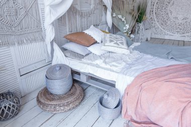 Bali tarzı yatak odasının içi. Dekorasyon için bir sürü tekstil ve yumuşak pastel renklerde hasır eşyalar içeren tenteli yatak.