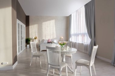 Açık renkli, lüks ve pahalı bir apartman dairesi. Minimum tasarım, yemek alanı ve misafir odası olan modern yatak odası..