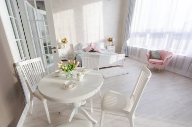 Açık renkli, lüks ve pahalı bir apartman dairesi. Minimum tasarım, yemek alanı ve misafir odası olan modern yatak odası..