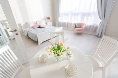 Açık renkli, lüks ve pahalı bir apartman dairesi. Minimum tasarım, yemek alanı ve misafir odası olan modern yatak odası..