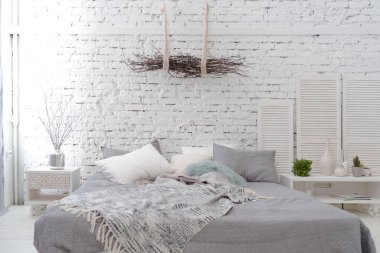 Geniş, şık, modern, beyaz ve açık renkli çatı katı dairesi. Güneş ışığıyla dolu büyük bir oda. tuğla duvar, ahşap zemin, raf, palet yatak ve büyük pencere. Her şey beyaz ve gri renkli..