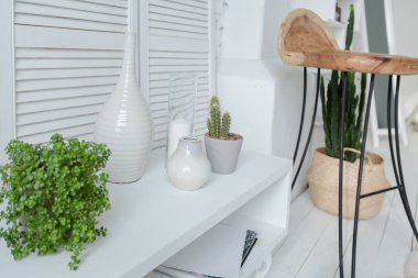 Geniş, şık, modern, beyaz ve açık renkli çatı katı dairesi. Güneş ışığıyla dolu büyük bir oda. tuğla duvar, ahşap zemin, raf, palet yatak ve büyük pencere. Her şey beyaz ve gri renkli..