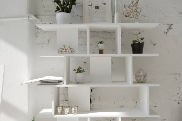 Spacious stylish modern trendy loft apartment in white and light colors. a large room full of sunlight. brick wall, wood floor, shelving, pallet bed and huge window. everything is white with gray tints.