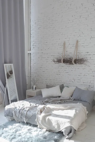 白と光の色で広々としたスタイリッシュなモダンなトレンディーなロフトアパート 陽射しの多い広い部屋です レンガの壁 木の床 パレットベッド 巨大な窓 すべてが灰色の色合いで白です — ストック写真