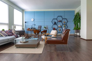 Mavi ve bej renkli, büyük pencereli ve gün ışığında minimalizm tarzında oturma alanı olan kişisel stüdyo ofisinin modern modaya uygun yaratıcı tasarımı