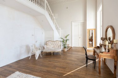 İki katlı, balkon tarzı dekoratif eşyalarla dolu, parlak bir dairede modern bir oda. Beyaz duvarlar, ahşap döşemeler ve eski mobilyalar.