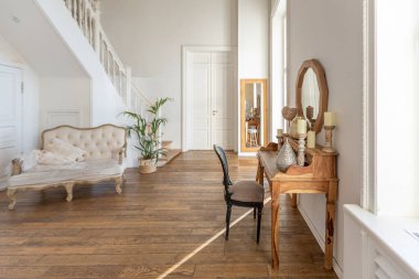 İki katlı, balkon tarzı dekoratif eşyalarla dolu, parlak bir dairede modern bir oda. Beyaz duvarlar, ahşap döşemeler ve eski mobilyalar.